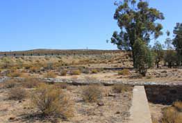 The ruins of the Klipfontein Hotel at Anenous Pass in the Northern Cape, South Africa, featuring stone walls and a water tower once used for Port Nolloth railway locomotives